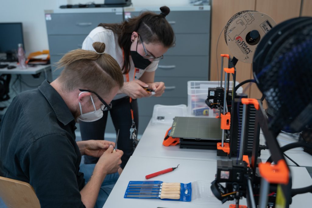 DigiLab-Mitarbeiterin erklärt einem Besucher den 3D-Drucker